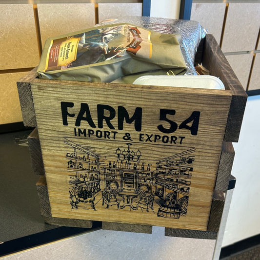 A wooden crate labeled 'FARM 54 IMPORT & EXPORT' with a printed illustration on the front, holding packaged goods.